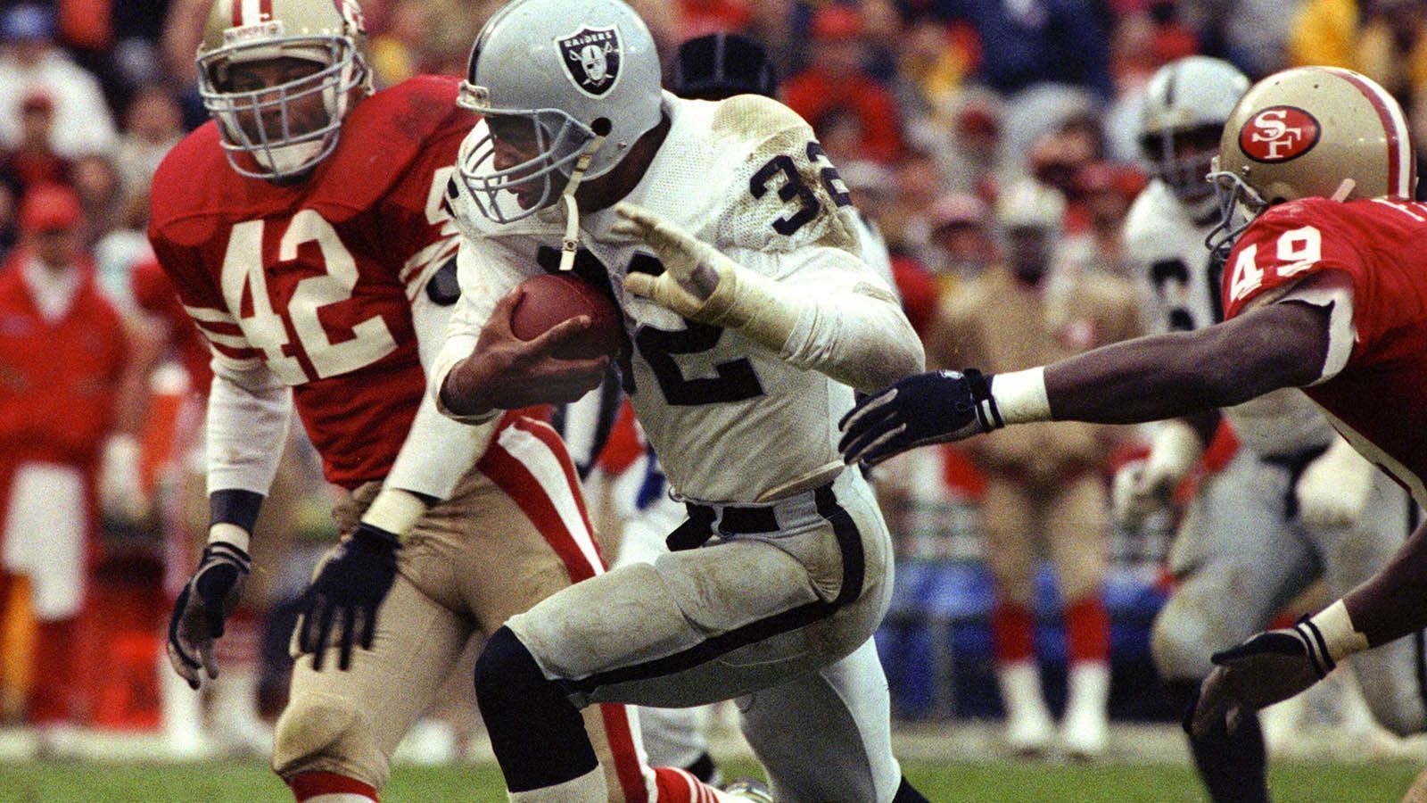 
                <strong>Platz 9 (geteilt): Saison 1983 - Punkteschnitt: 21,8</strong><br>
                Ebenfalls 21,8 Punkte im Schnitt erzielten die Teams in der Saison 1983. Den Titel sicherten sich die Raiders, die damals noch in Los Angeles ansässig waren und im Endspiel die Washington Redskins mit 38:9 schlugen. Super-Bowl-MVP wurde Running Back Marcus Allen (Bild). Gute Defense setzte sich in dieser Spielzeit nicht durch, denn beide Super-Bowl-Teilnehmer gehörten in den Defensiv-Statistiken nur zum Mittelmaß der Liga. In Sachen Scoring-Offense gehörten sie mit 541 (Redskins) beziehungsweise 442 (Raiders) Punkten aus 16 Spielen zu den Top 3.
              