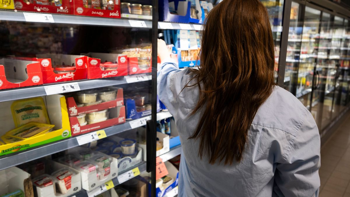 Eine Frau greift nach einem Lebensmittel an einem Kühlregal eines Supermarkts.