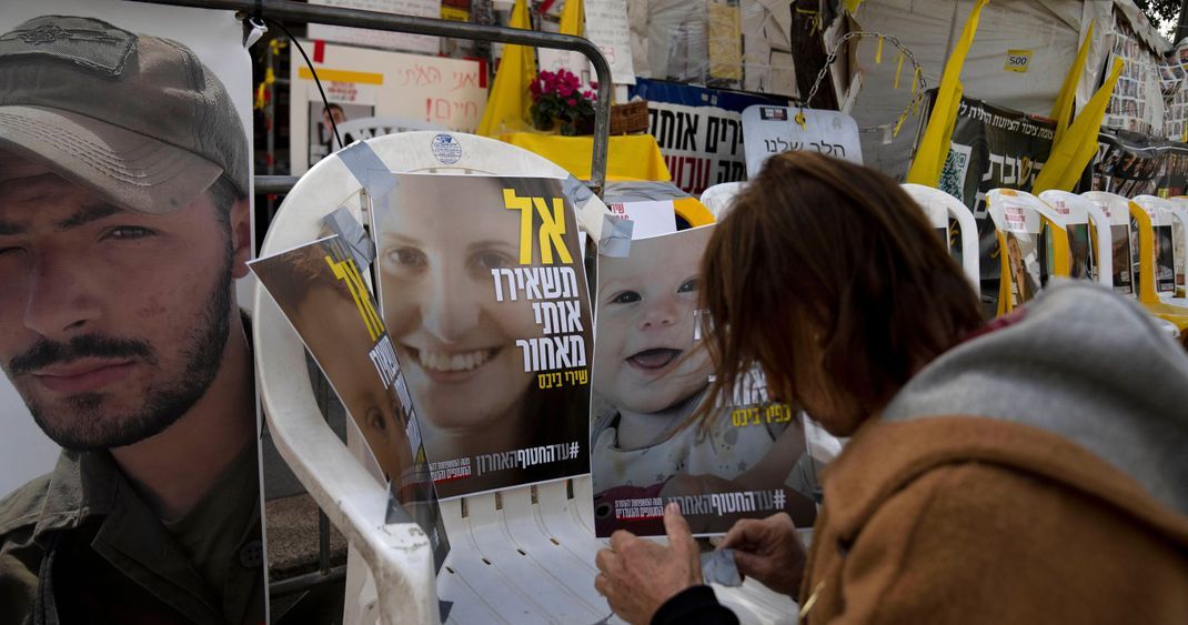 Eine Frau klebt auf einen leeren Stuhl Plakate von Shiri Bibas und ihren Söhnen Ariel und Kfir, die am 7. Oktober 2023 von Mitgliedern der Terrororganisation Hamas als Geiseln genommen wurden. 