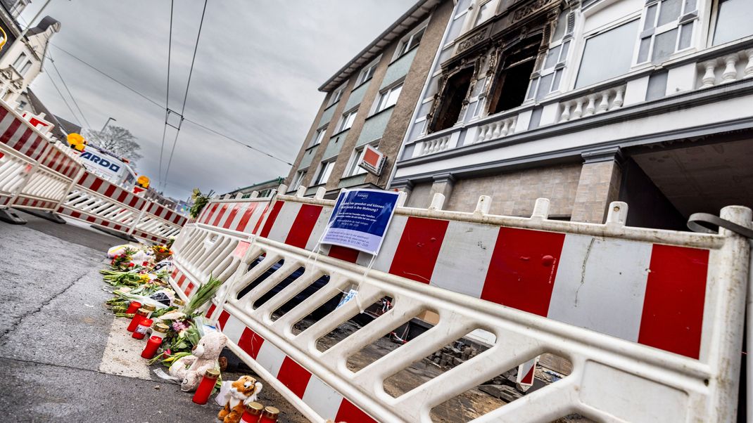 Blumen und Kerzen liegen vor dem Brandort in Solingen nach dem Pressestatement der Staatsanwaltschaft Wuppertal.