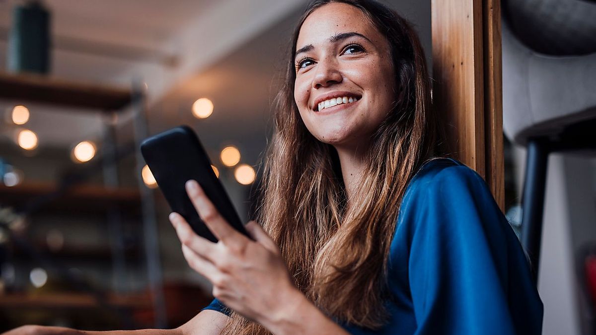 Happy businesswoman with smart phone at office