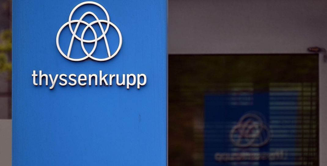 Das Thyssenkrupp-Logo steht vor einer Werksanlage.