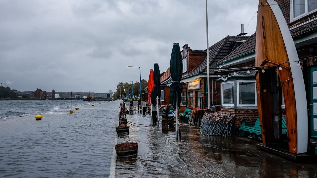 Die Straße vor den Cafés und Geschäften am Tiessenkai im Kieler Stadtteil Holtenau ist vollständig von der Ostsee überflutet.