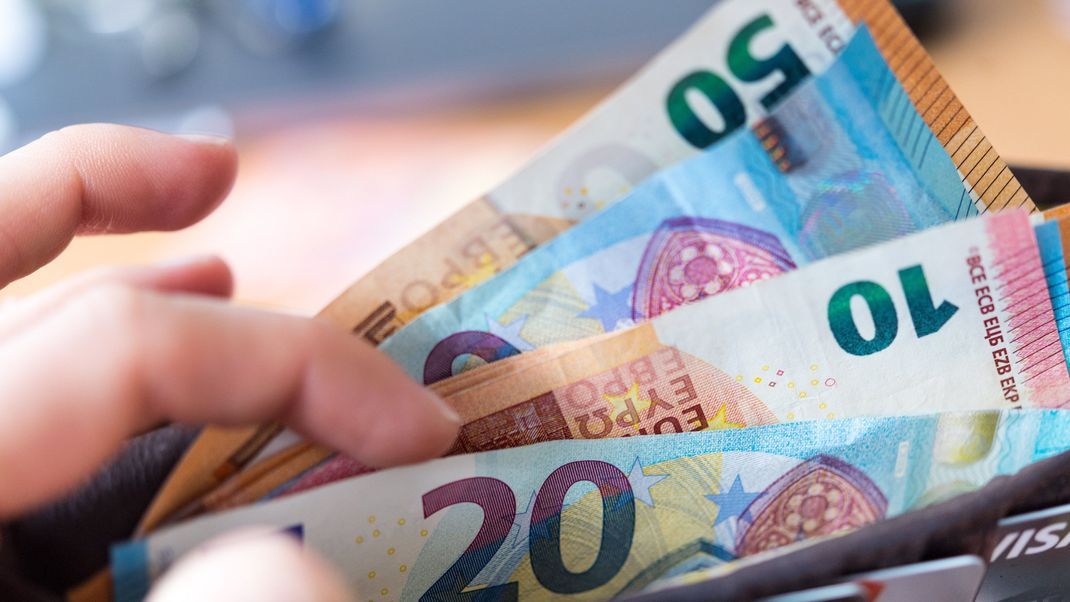 Eine Frau hält eine Geldbörse mit Banknoten in der Hand.