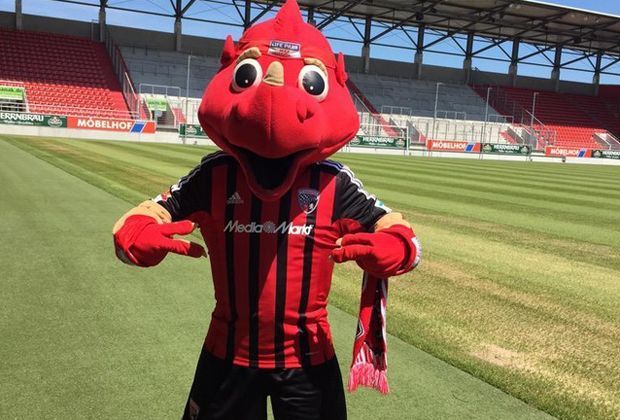 
                <strong>Das neue Heimtrikot des FC Ingolstadt</strong><br>
                So sieht es aus: Schanzi, das Maskottchen, präsentiert das erste Bundesliga-Trikot der Geschichte des FC Ingolstadt. Das Trikot ist traditionell in rot-schwarzen Längsstreifen gehalten. Nur ein neuer Sponsor ziert die Brust.
              