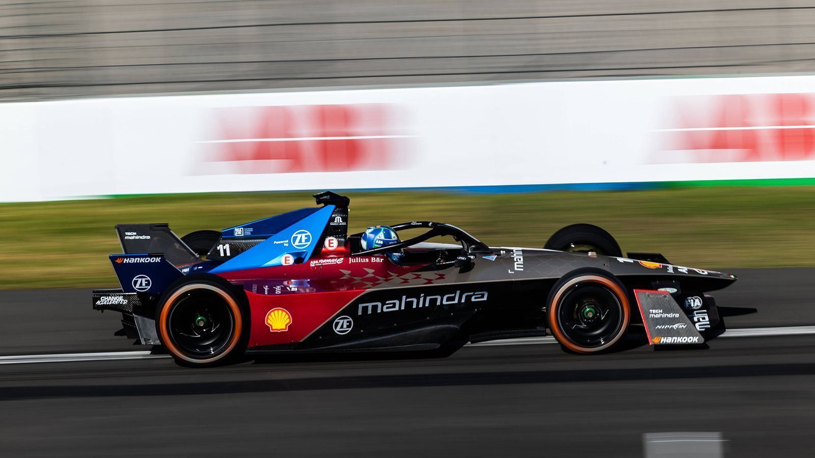 
                <strong>Mahindra Racing </strong><br>
                Mahindra Racing ist seit Gründung der Formel E mit von der Partie. 2023 überzeugt der Bolide von Oliver Rowland und Lucas di Grassi mit einer Mischung aus den Farben Schwarz, Rot und Blau.
              
