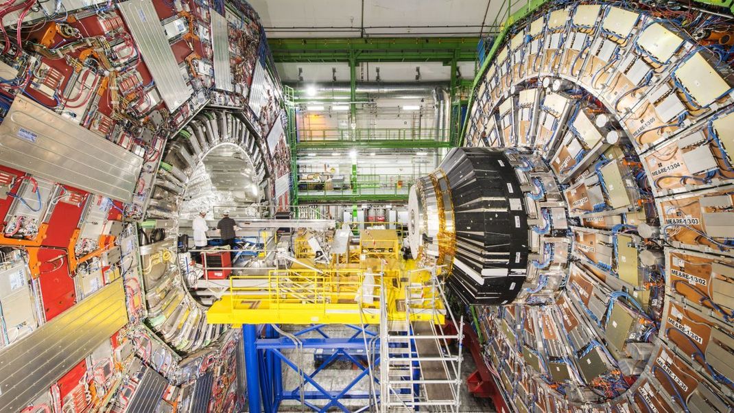 Statt nur danach zu suchen, wollen Wissenschaftler:innen dunkle Materie auch selbst erzeugen. Nach drei Jahren Umbau schießen Forschende in einem fast 30 Kilometer langen unterirdischen Ringtunnel des Large Hadron Collider in Genf Atomkerne aufeinander. Bisher erzeugte der Teilchenbeschleuniger schon Elementarteilchen, welche Physiker in den 1960er Jahren vorhersagten - aber bis heute noch keine dunkle Materie. Im Bild zu sehen ist nur der Detektor. Das 22 Meter breite Gerät wurde von der Universität Mainz mitgebaut und misst die Teilchen, die bei den Kollisionen entstehen. 