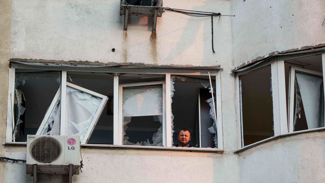 Ukraine, Kiew: Ein Mann blickt aus dem Fenster eines mehrstöckigen Wohnhauses, das bei einem russischen Drohnenangriff auf Kiew, Ukraine, beschädigt wurde. 