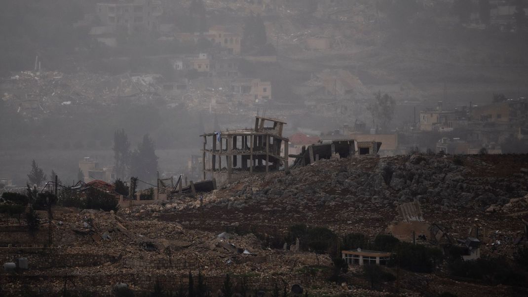 25. November 2024, Libanon: Zerstörte Gebäude stehen auf dem Gelände eines Dorfes im Südlibanon, gesehen vom Norden Israels aus.