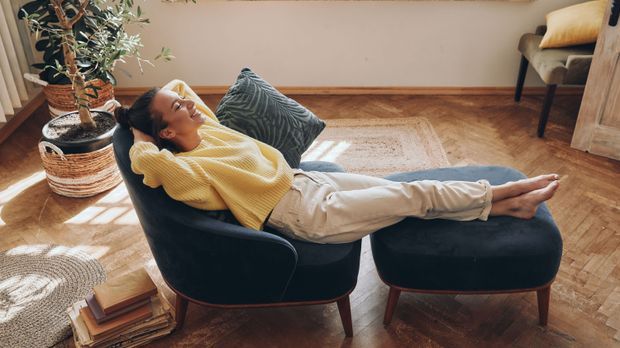 Top view of happy woman keeping eyes closed while relaxing in comfortable chair at home