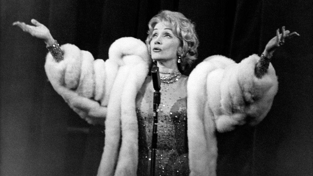 Als trüge sie einen Hauch von Nichts. Nur im (heute strittigen, damals akzeptierten) Pelzmantel und einem Naked Dress, besetzt von hunderten Perlen, stand die Dietrich auf der Bühne. Das Kleid war ein Novum und zeigte wieder, was für eine Fashionicon war.
