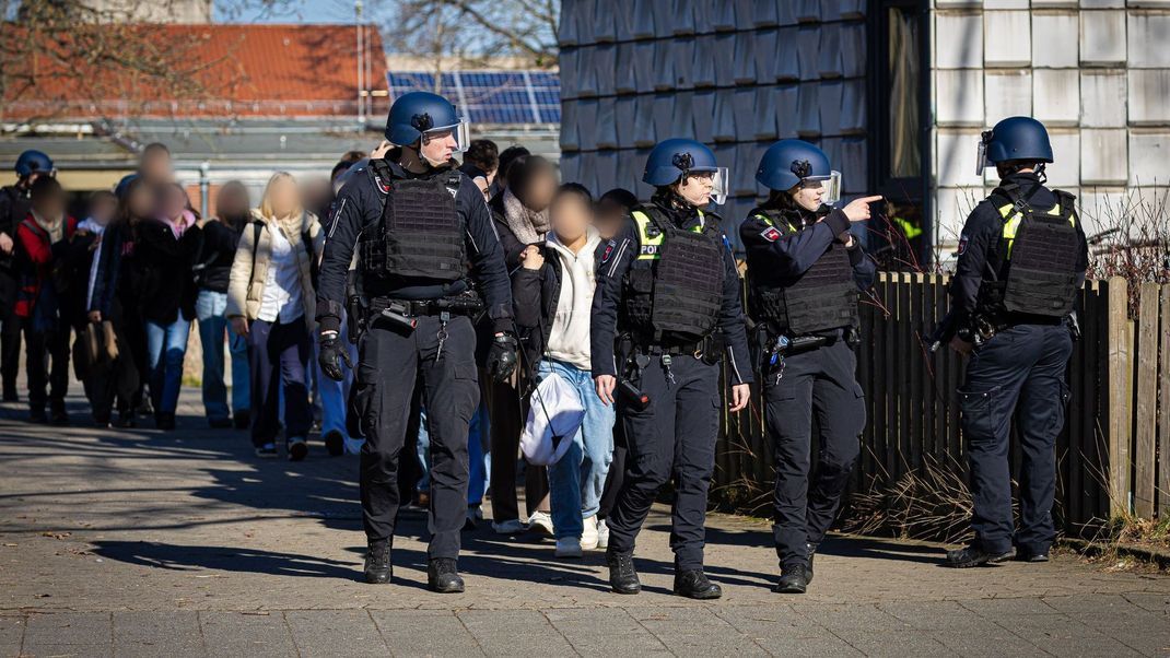 Mehrere Beamt:innen durchsuchen das Schulgebäude in Braunschweig, das einen Amok-Alarm ausgelöst hat.