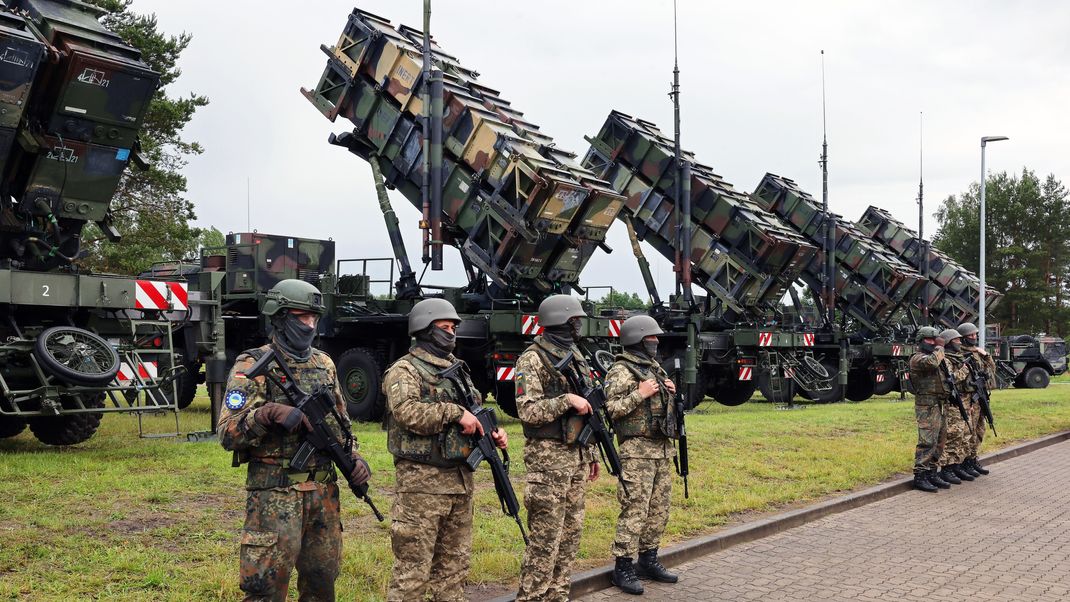 11. Juni 2024, Mecklenburg-Vorpommern: Deutsche und ukrainische Soldaten stehen beim Besuch des ukrainischen Präsidenten Selenskyj auf einem Truppenübungsplatz vor Flugabwehrraketensystemen des Typs Patriot. 