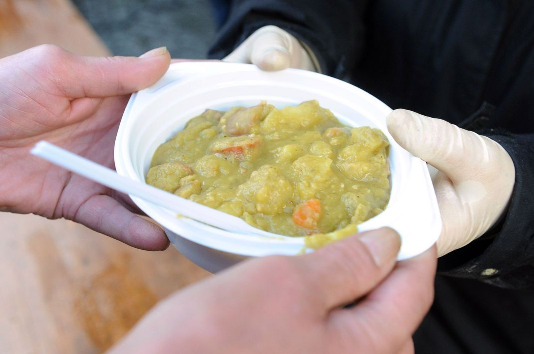 Eine Erbsensuppe wird an einen Gast überreicht.