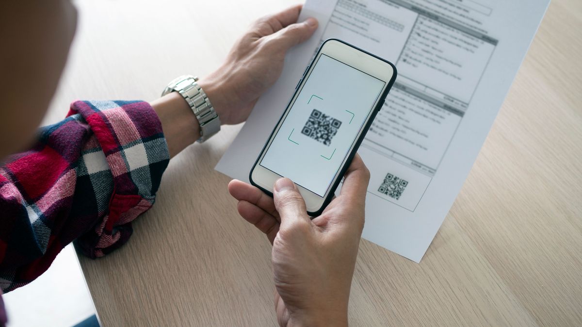 A man uses a smartphone to scan the QR code to pay monthly credit card bills after receiving an invoice sent to home. Online bill payment concept