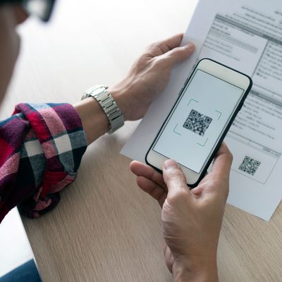 A man uses a smartphone to scan the QR code to pay monthly credit card bills after receiving an invoice sent to home. Online bill payment concept