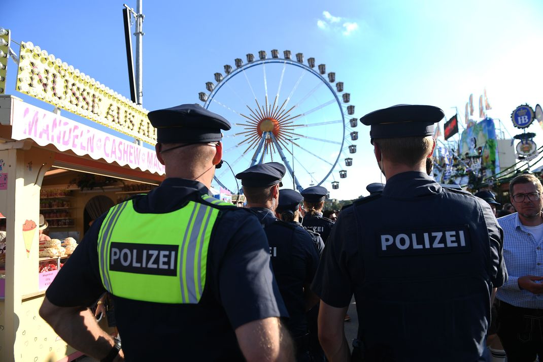 Polizisten stehen auf dem Oktoberfest vor dem Riesenrad.