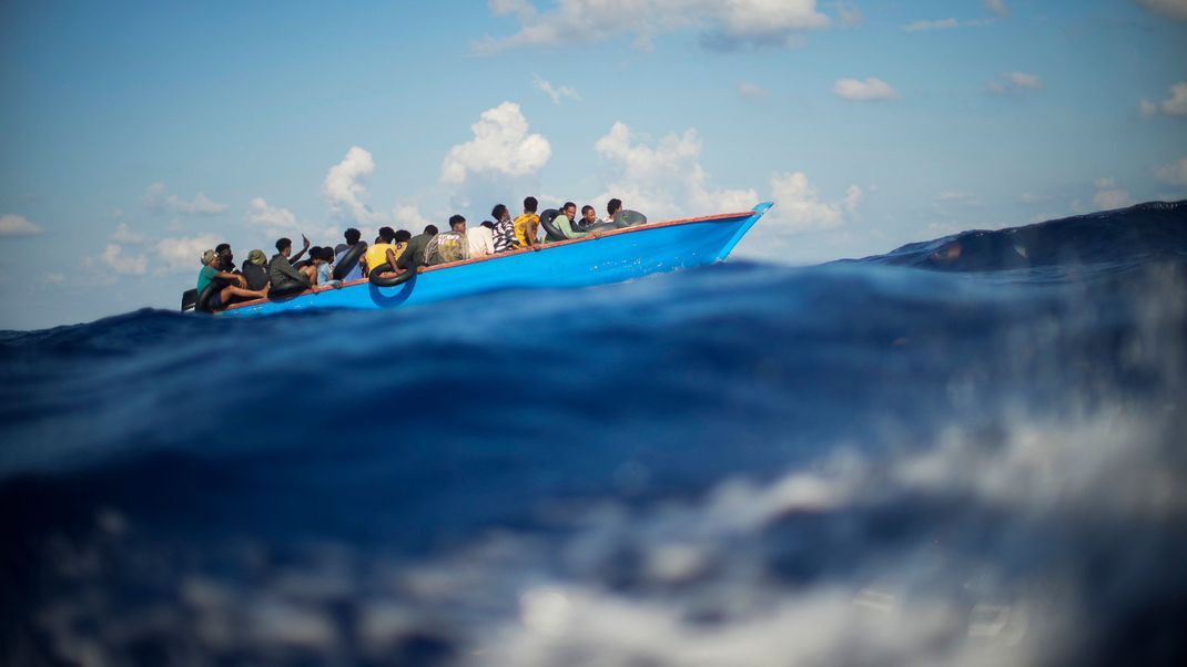 Migranten sitzen in einem Holzboot südlich der italienischen Insel Lampedusa auf dem Mittelmeer.&nbsp;