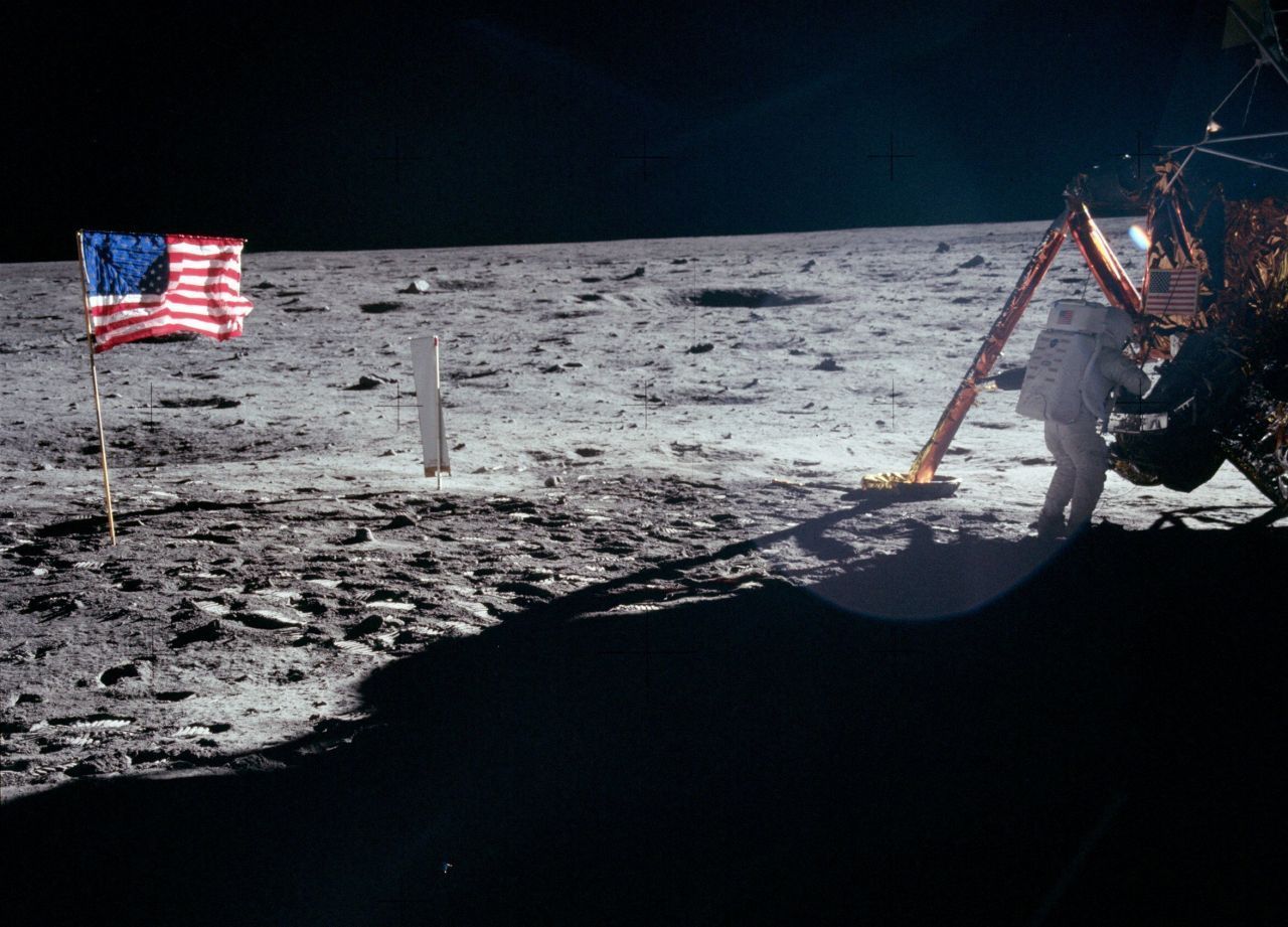 Neil Armstrong arbeitet am Fuß der Landefähre Eagle, die US-Flagge weht.