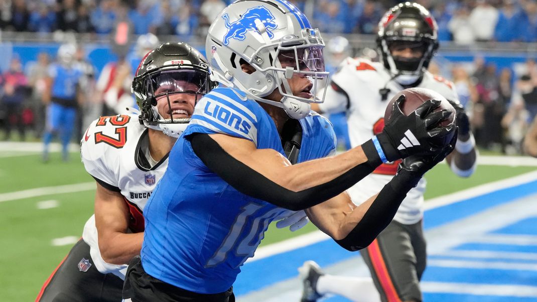 21.01.2024, USA, Detroit: American Football: Profiliga NFL, Detroit Lions - Tampa Bay Buccaneers, Play-off-Runde, Viertelfinale. Detroit Lions Wide Receiver Amon-Ra St. Brown (vorne) fängt einen Touchdown-Pass vor Tampa Bay Buccaneers Cornerback Zyon McCollum (27). 