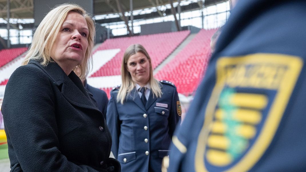 Nancy Faeser (SPD, l), Bundesinnenministerin, unterhält sich in der Leipziger Arena mit Vertretern der Polizei.