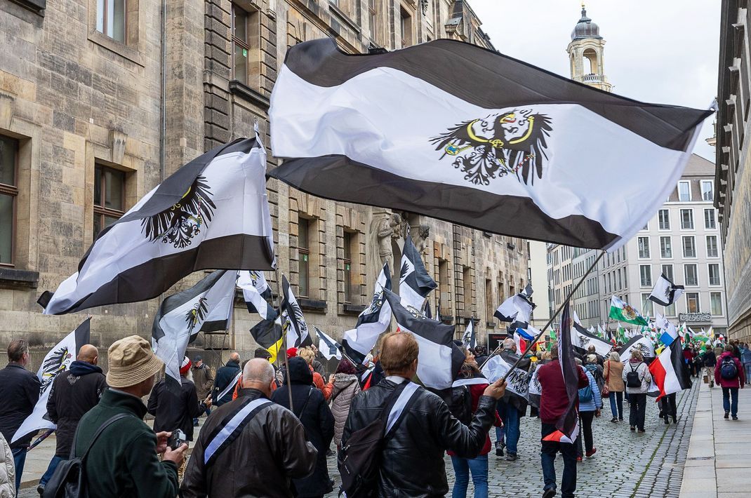 Mehrere hundert Teilnehmer einer Demonstration ziehen mit Flaggen vom Königreich Preußen (schwarz-weiß-schwarz mit Adler) durch die Innenstadt. Rund 280 Einsatzkräfte haben am Donnerstag in acht Bundesländern mehrere Objekte im Zusammenhang mit Ermittlungen gegen «Reichsbürger» durchsucht. (zu dpa: «Razzia gegen «Reichsbürger» in acht Bundesländern»)