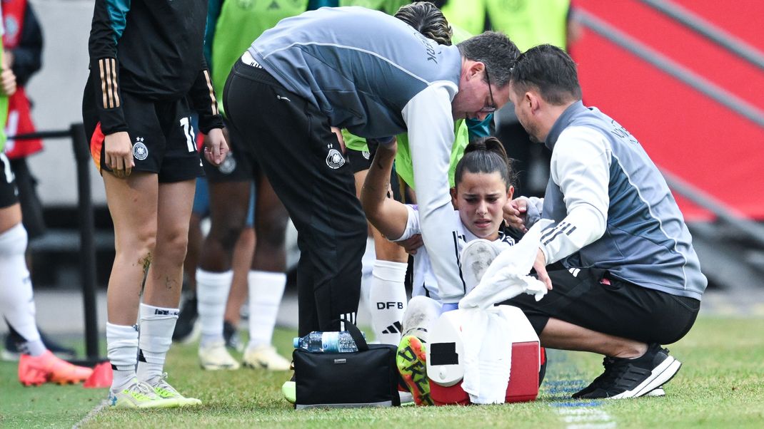 Deutschlands Lena Oberdorf (M) wird von Teamärzten vom Feld gebracht. 