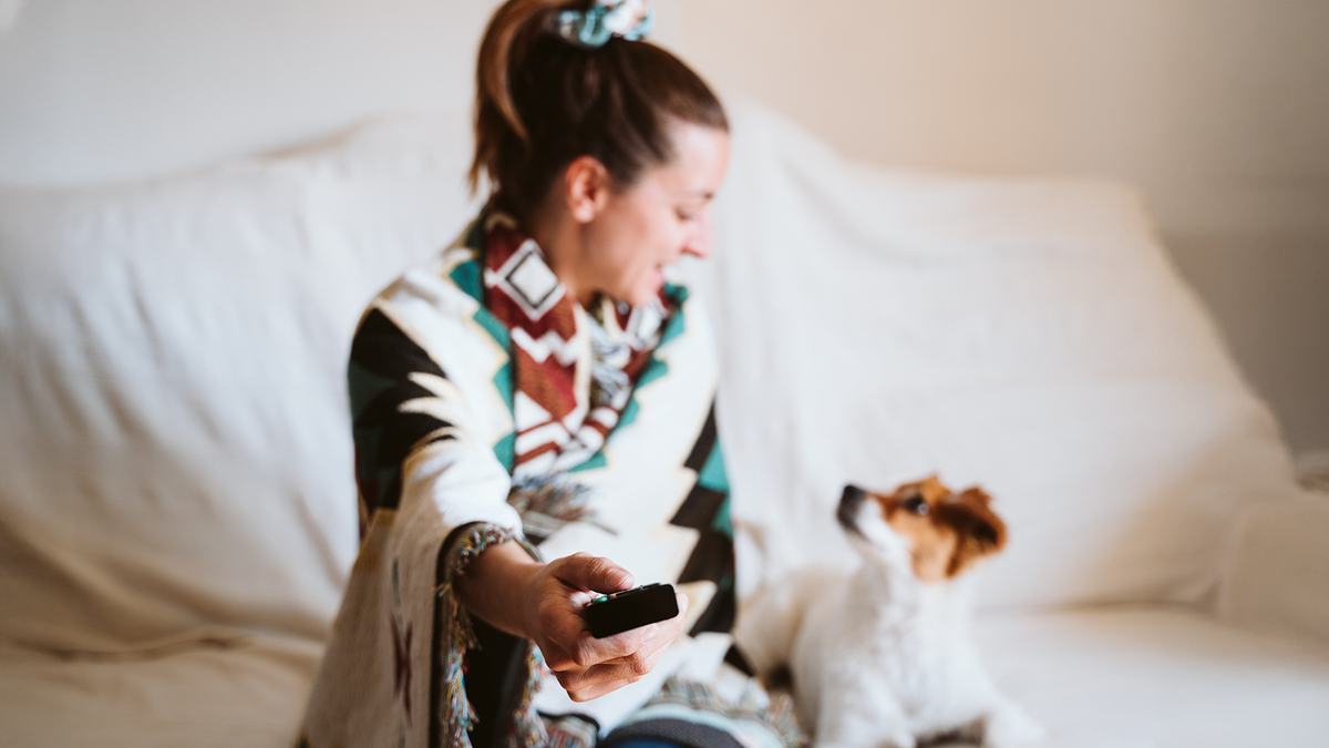 Frau mit Fernbedienung und kleinem Hund 