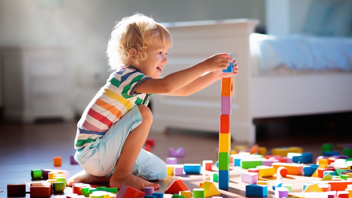 Child playing with colorful toy blocks. Kids play.
