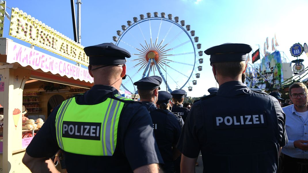 Polizisten stehen auf dem Oktoberfest vor dem Riesenrad. 