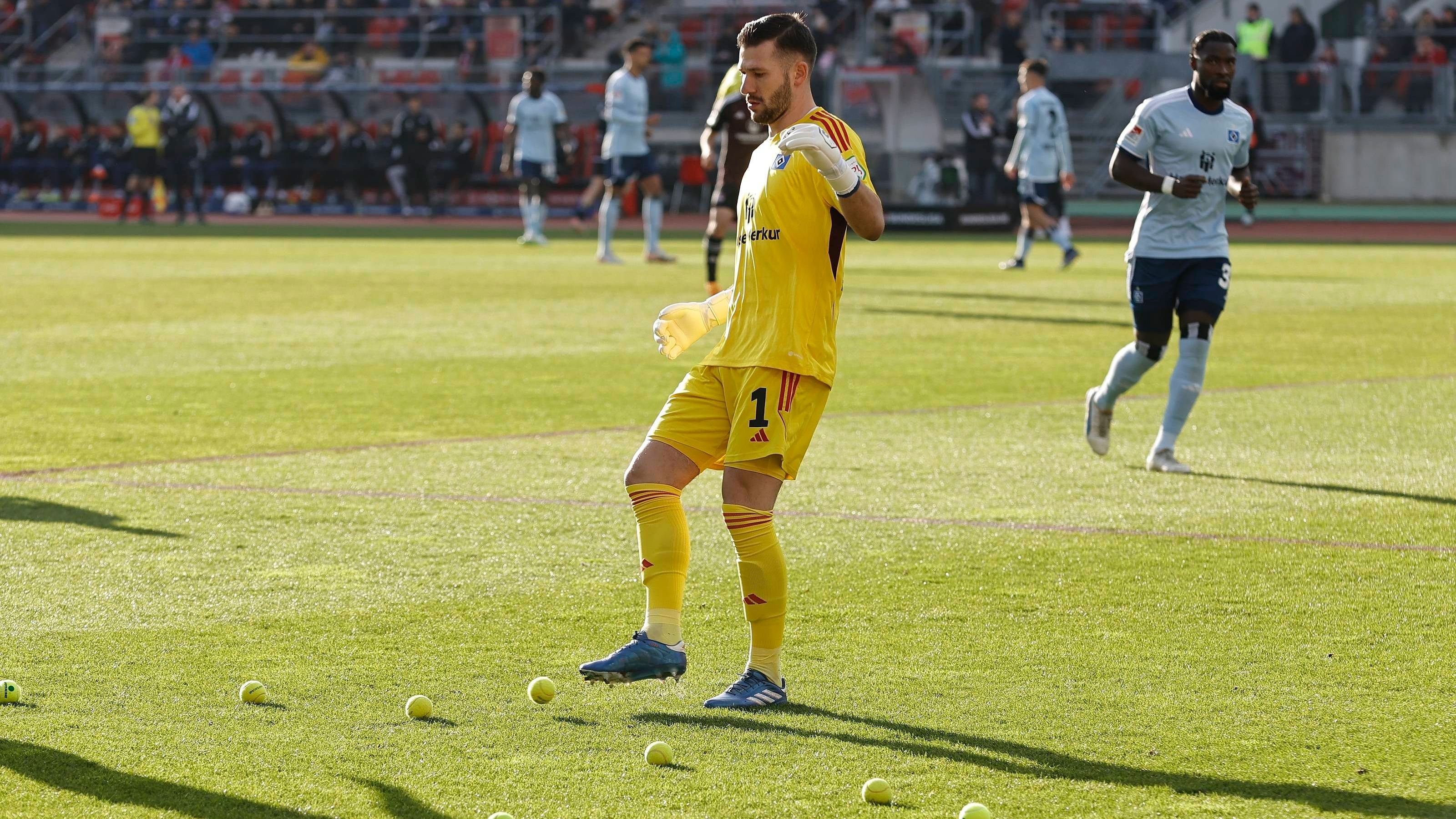 <strong>Tennisbälle in Nürnberg</strong><br>Während des Zweitligaspiels zwischen dem 1. FC Nürnberg und dem Hamburger SV werfen Zuschauer zahllose Tennisbälle auf den Rasen. Die Partie wird kurz unterbrochen. Gäste-Keeper Daniel Heuer Fernandes räumt auf.