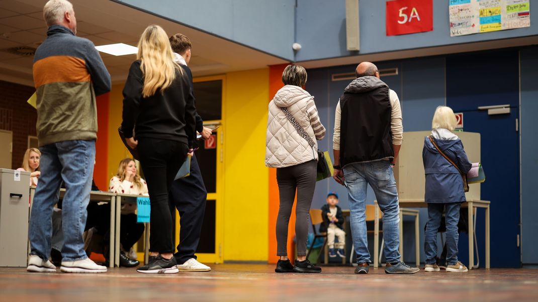 Wähler:innen stehen in einem Wahlbüro in NRW an.