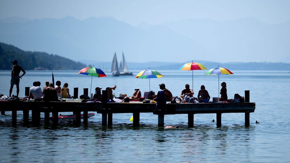 Menschen genießen das warme Wetter und den Sonnenschein auf einem Steg am Starnberger See.