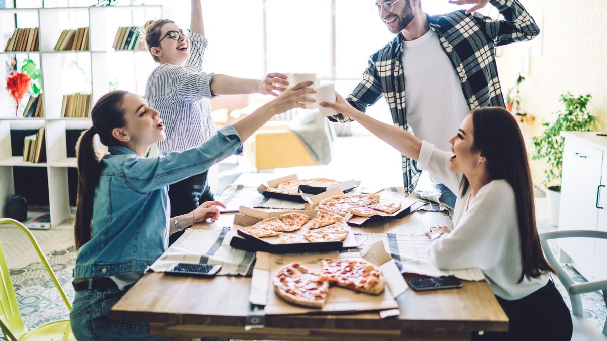 Enthusiastic mates raising toast while having party in flat