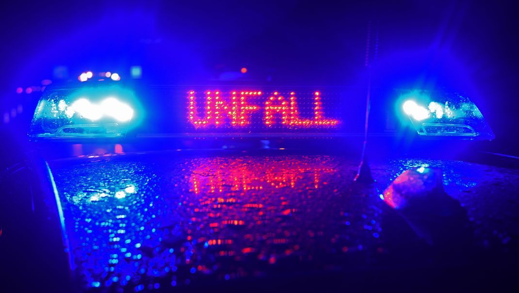 Auf der A8 spiegeln sich während einer Unfallaufnahme das Blaulicht und der LED- Schriftzug "Unfall" auf dem nassen Dach eines Polizestreifenwagens.