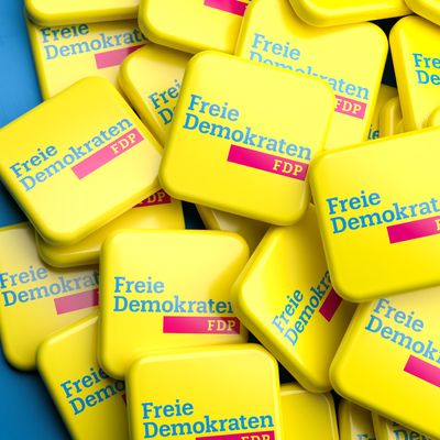 Logos of the liberal German political party FDP on a heap on a table. Copy space. Web banner format.