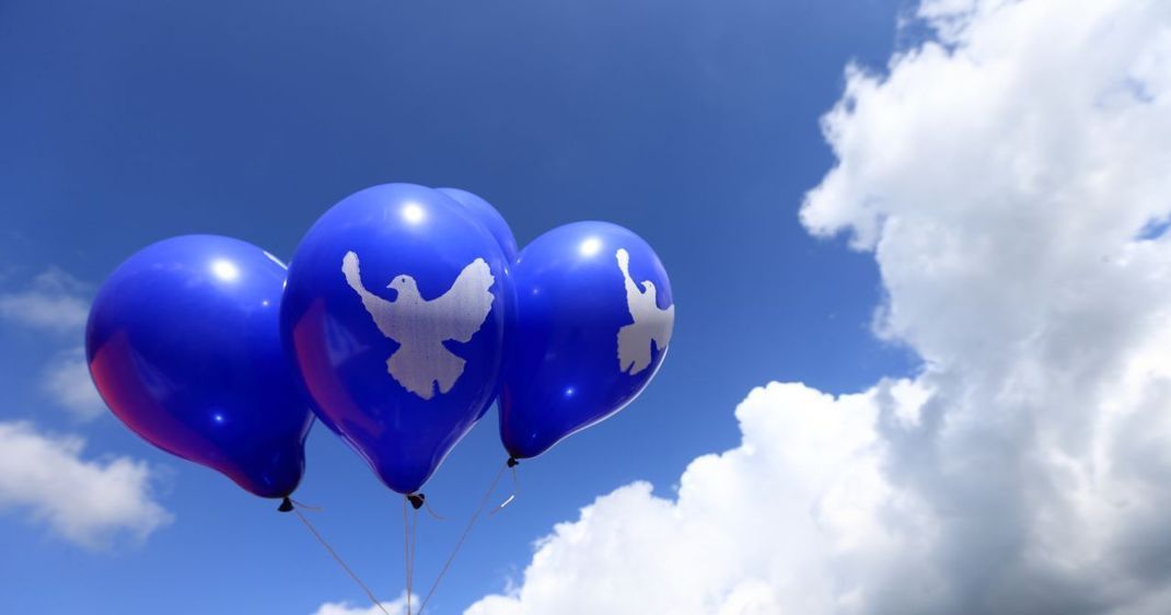 Blaue Luftballons mit dem Symbol einer weißen Friedenstaube schweben während einer Friedensaktion 2014 in Letzlingen (Sachsen-Anhalt) in der Luft.