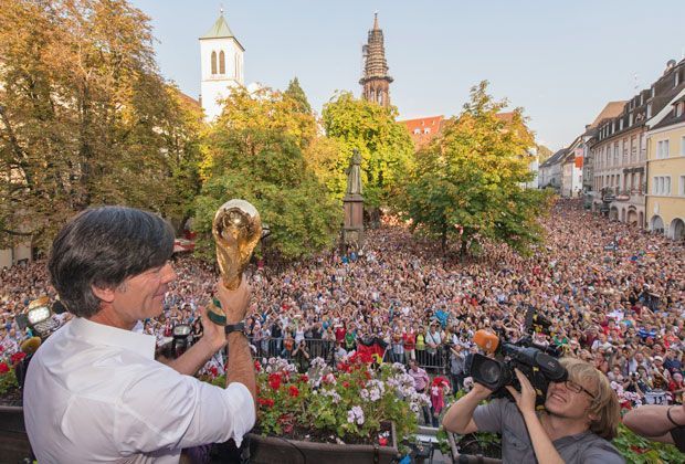 
                <strong>Freiburg feiert "Popstar" Löw</strong><br>
                Wahnsinn! Die ganz Stadt scheint sich versammelt zu haben, nur um einen Blick auf Löw und den WM-Pokal werfen zu können. Rund um den Rathausplatz war Bewegungsfreiheit wohl Mangelware.
              