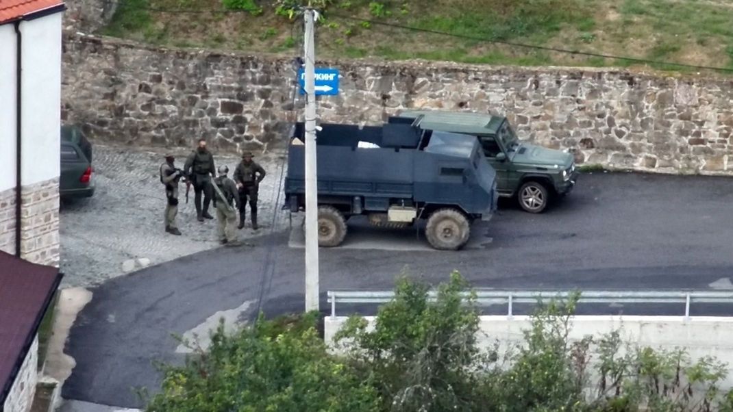 Bewaffnete, maskierte Männer stehen neben einem gepanzerten Wagen in Banjska. Das Foto wurde von der kosovarischen Polizei zur Verfügung gestellt.