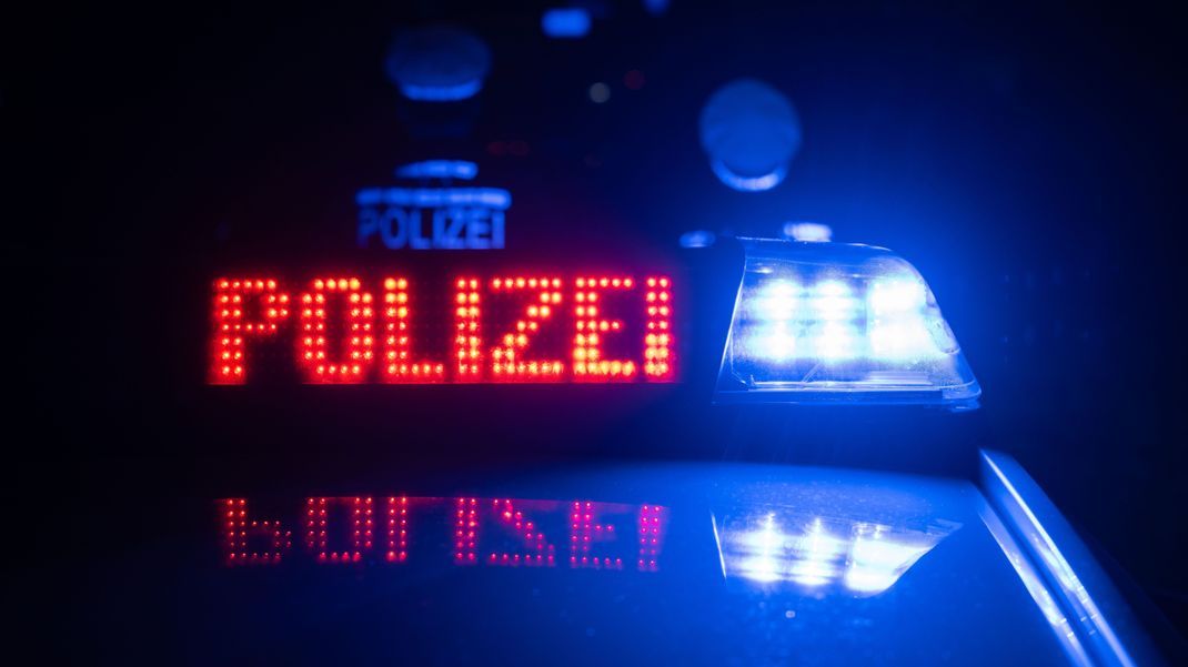 Zwei Polizisten stehen im Rahmen eines Fototermins vor einem Polizeifahrzeug (gestellte Szene). 