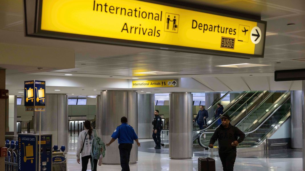 9. Juni 2025, USA, Newark: Menschen mit Koffern gehen durch das internationale Terminal des Newark Liberty International Airport. 
