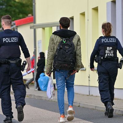 Polizeibeamte begleiten einen Flüchtling in einer Erstaufnahmeeinrichtung für Asylbewerber