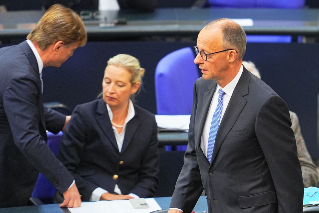 Der designierte Bundeskanzler Friedrich Merz (CDU, rechts) reagiert im Bundestag bei der Kanzlerwahl. Im Hintergrund unterhalten sich Bernd Baumann, erster parlamentarischer Geschäftsführer der AfD-Bundestagsfraktion, und Alice Weidel, Bundes- und Fraktionsvorsitzende der AfD.
