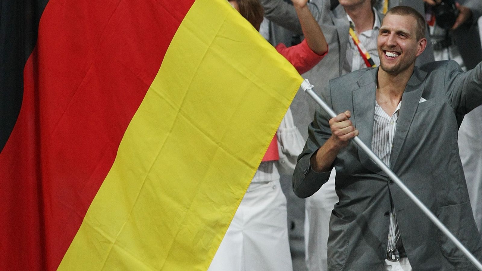 
                <strong>Dirk Nowitzki: Die Meilensteine seiner Karriere</strong><br>
                Bei den Olympischen Spielen 2008 scheidet die deutsche Nationalmannschaft bereits in der Gruppenphase aus, von den USA werden Nowitzki und Co. beim 57:106 böse verprügelt. Aber: Für Nowitzki ist es ein Höhepunkt seiner Karriere, die deutsche Olympia-Mannschaft als Fahnenträger anzuführen.
              