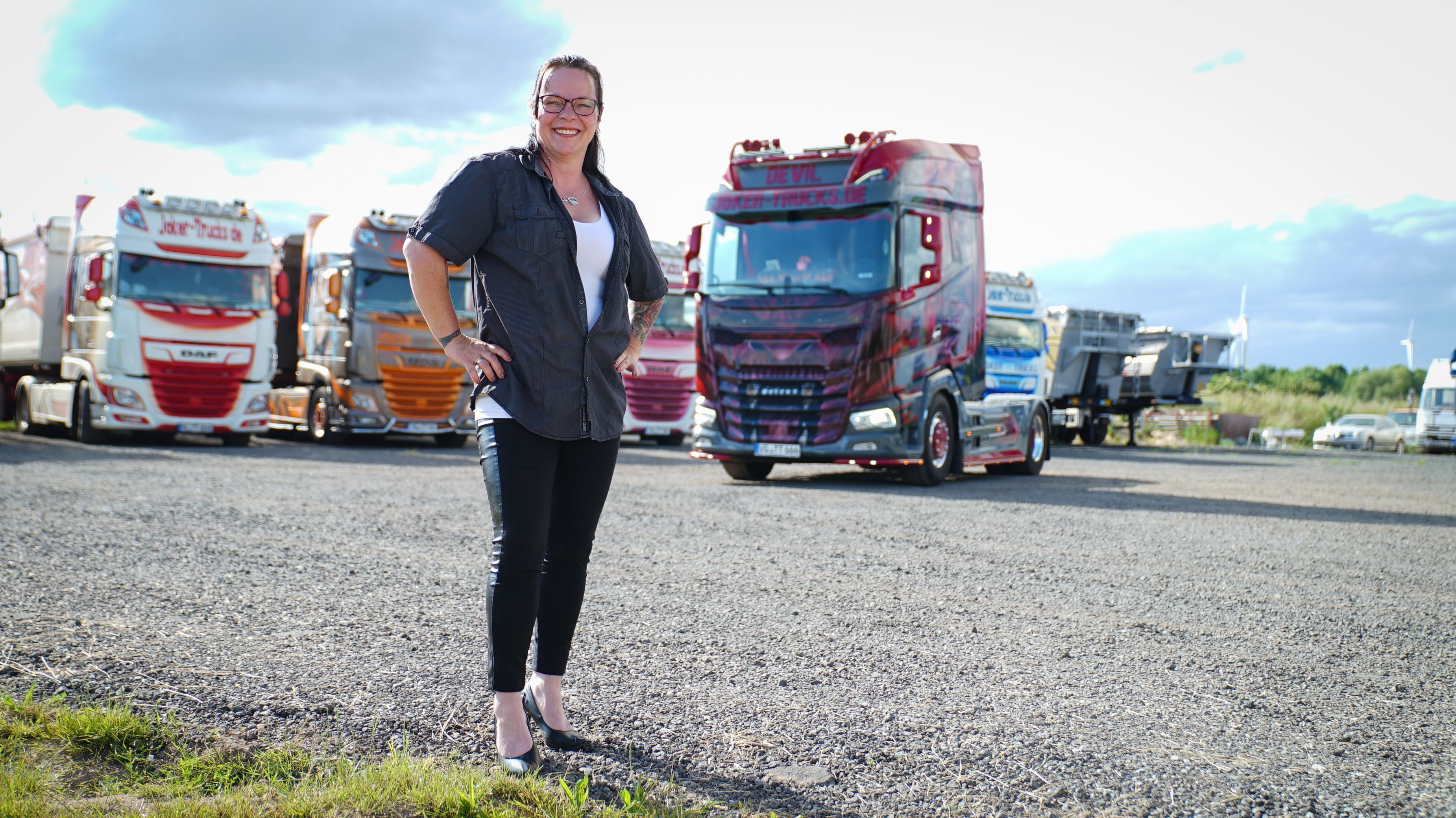 "Trucker Babe" Tamara steht vor ihren Trucks und lächelt in die Kamera. 