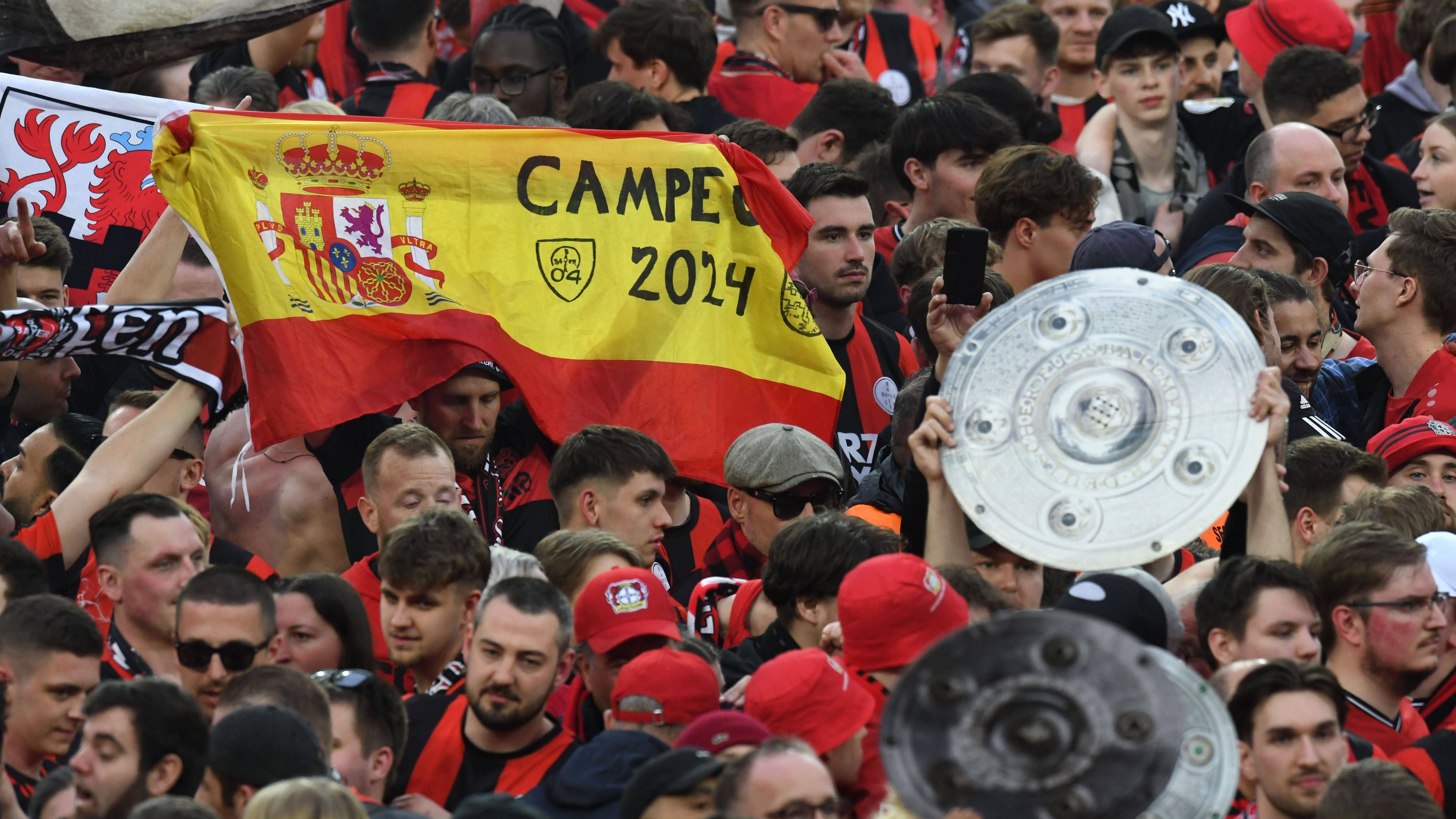 <strong>Bayer Leverkusen: Die besten Bilder der Meisterfeier</strong><br>Dass ihr Erfolgstrainer Spanier ist, zeigt die Bayer-Fangemeinde auf dem Rasen mit der entsprechenden Nationalflagge und der Aufschrift: "Campeon 2024". Übersetzung überflüssig.