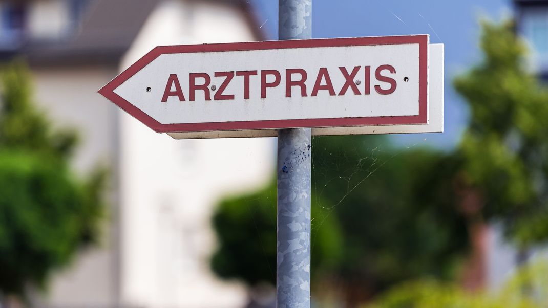 Ein Schild "Arztpraxis" steht an einer Straße in Wustermark in Brandenburg.