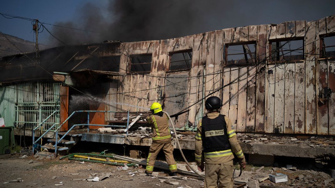 Feuerwehrleute arbeiten daran, ein Feuer zu löschen, nachdem eine aus dem Libanon abgefeuerte Rakete in einem Lager der Gemeinde Kiryat Shmona eingeschlagen ist.