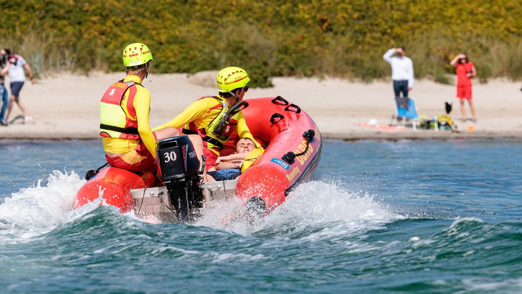 DLRG-Rettungsschwimmer bringen bei einer Übung einen Statisten zurück an den Strand.