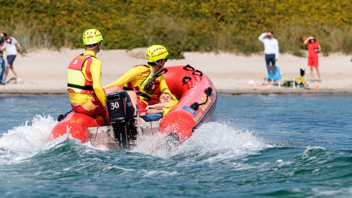 DLRG-Rettungsschwimmer bringen bei einer Übung einen Statisten zurück an den Strand.